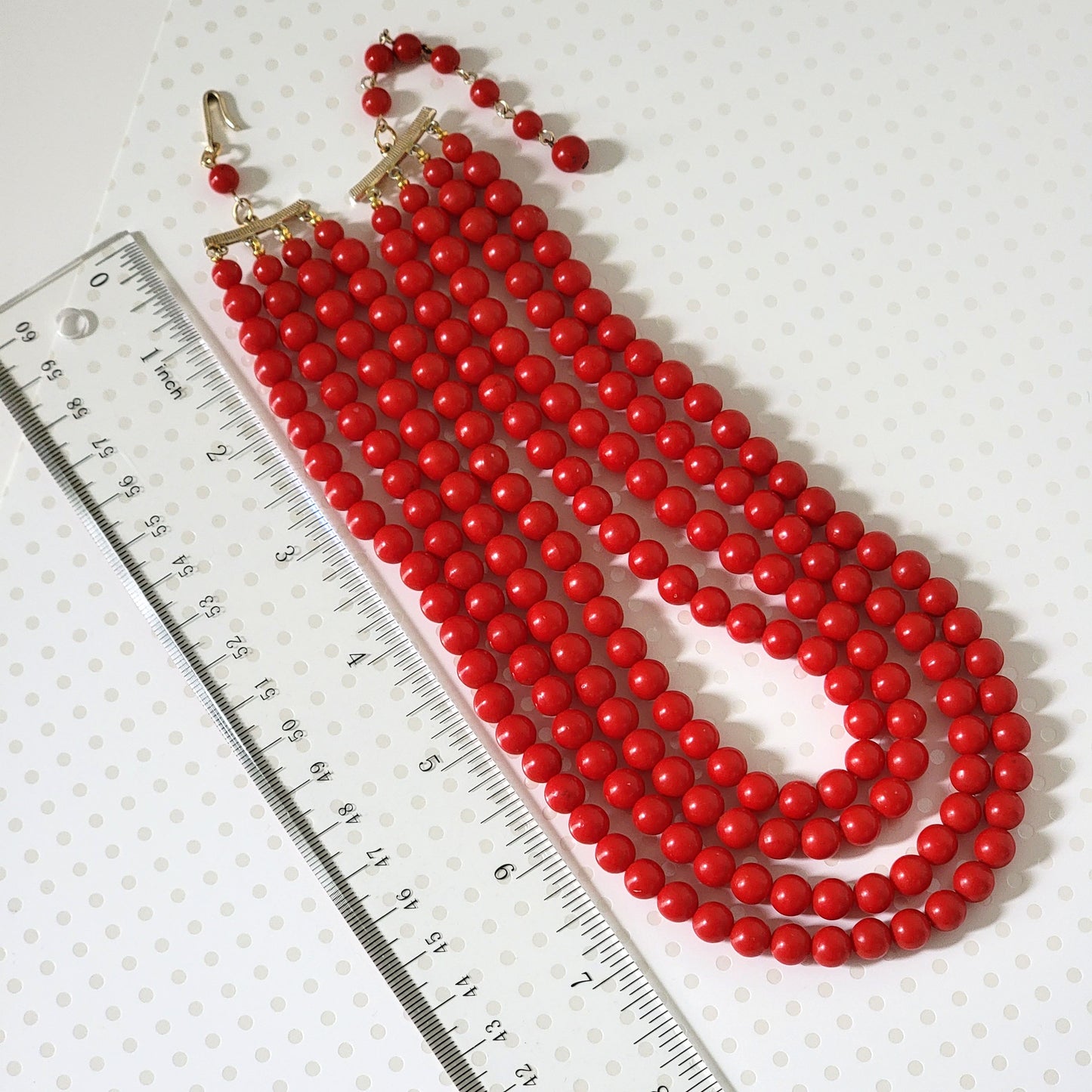 Vintage four-strand red plastic beaded choker, next to a ruler.