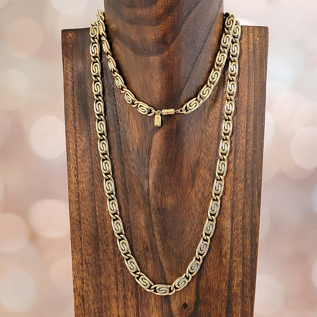 Thick gold tone snail chain on a stand.