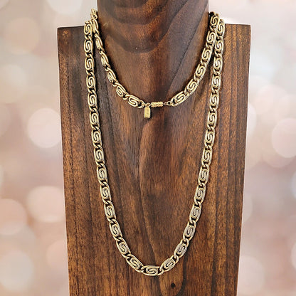 Thick gold tone snail chain on a stand.