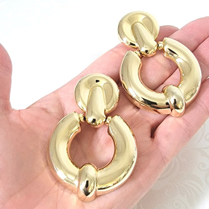 Big gold tone door knocker earrings, shown in hand, for size comparison.
