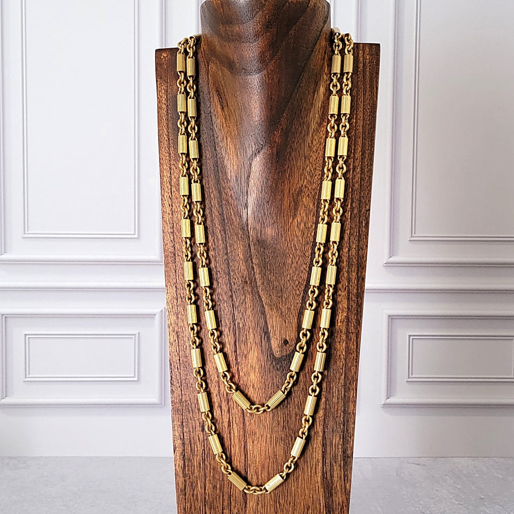 Long gold chain on a jewelry display stand.