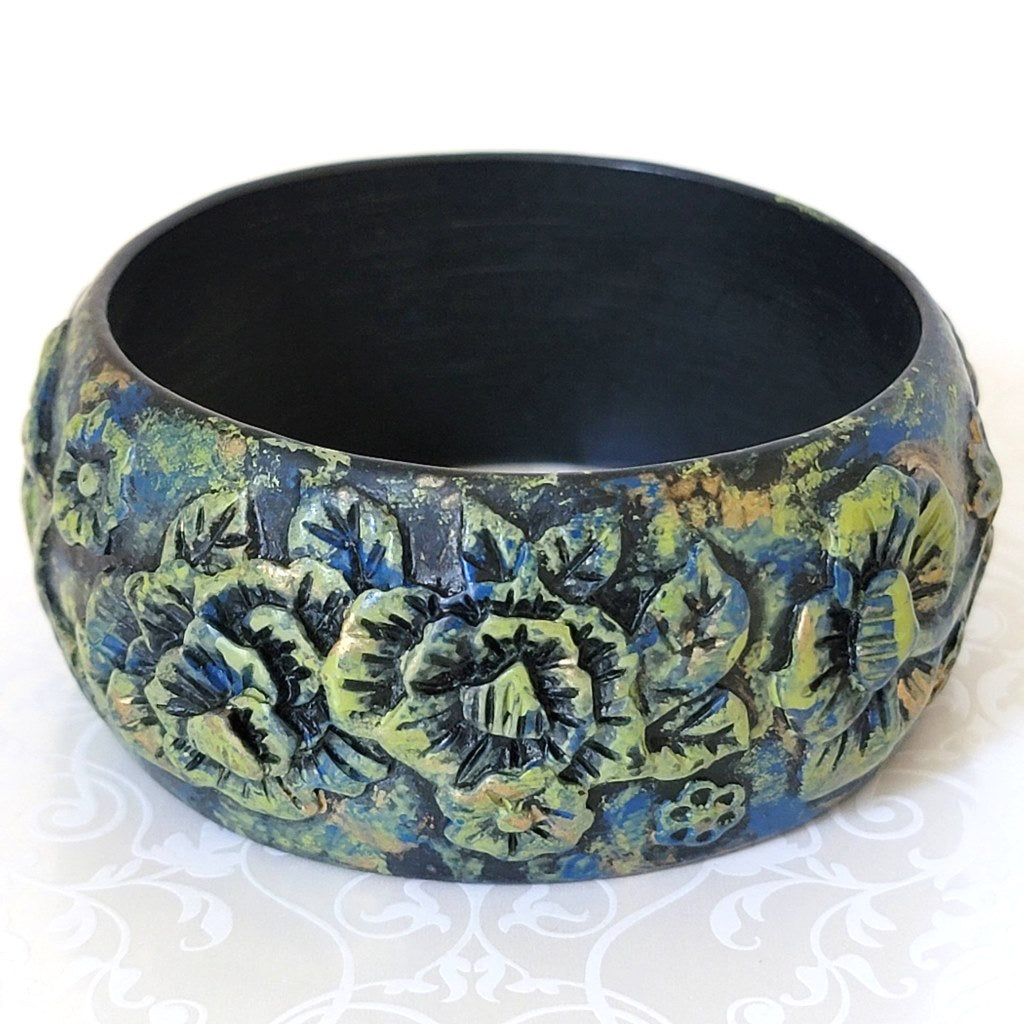 Goth style flower bracelet, in black molded resin, with green highlights and blue accents.