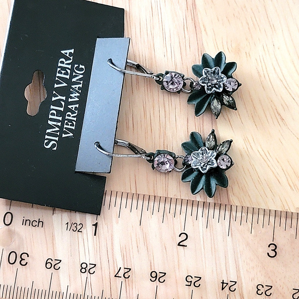 Green flower earrings next to a ruler.