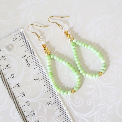 Green gemstone dangle earrings, with gold crystal accents, shown next to a ruler.