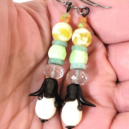 Gemstone dangle earrings, with black and white flowers, and green opals. Shown in hand, for size comparison.