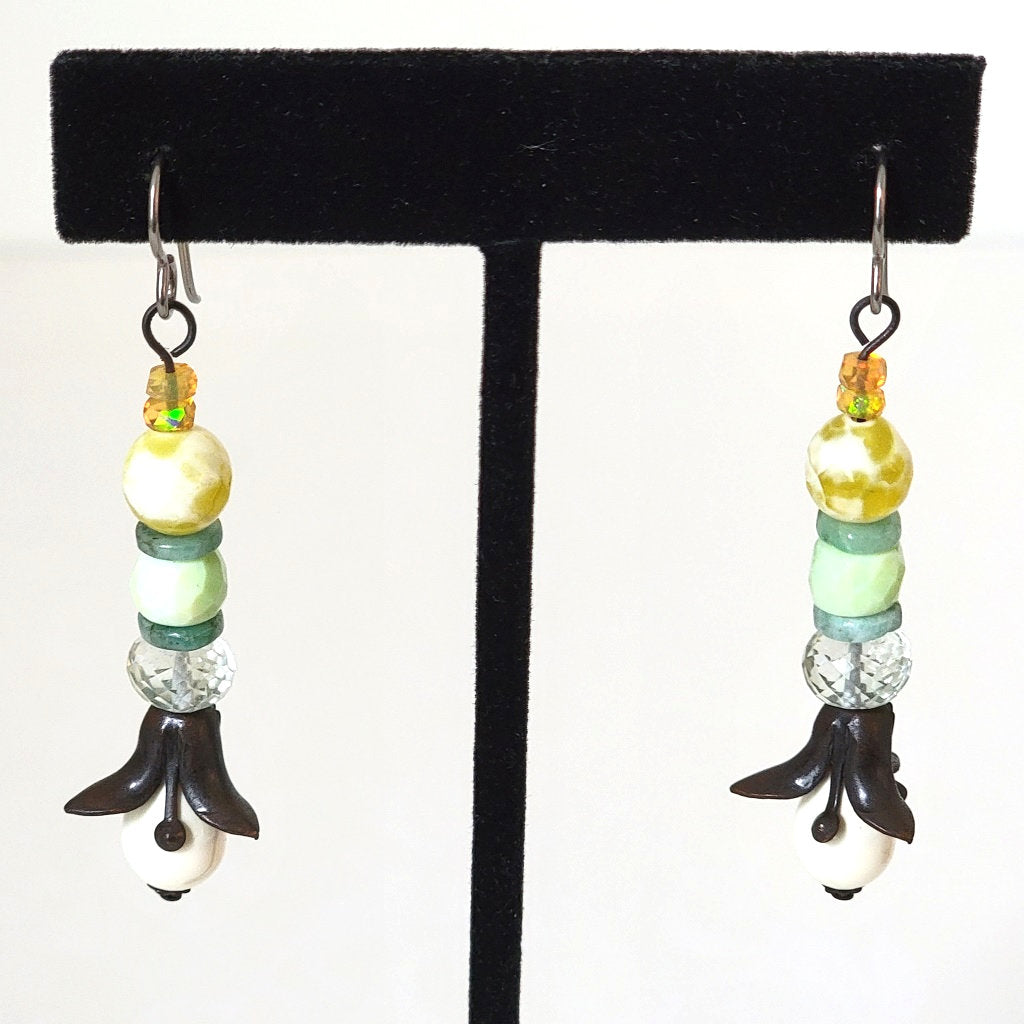 Long floral dangle earrings, with black brass petals, white glass, and yellow opals.