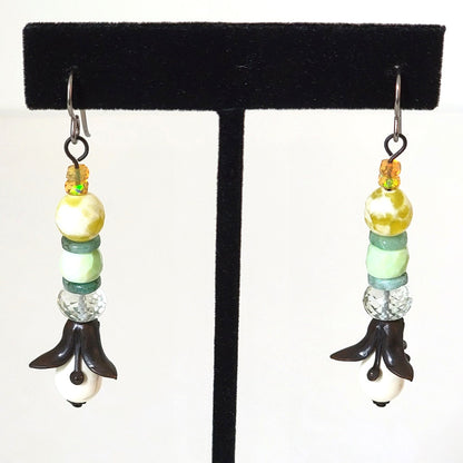 Long floral dangle earrings, with black brass petals, white glass, and yellow opals.