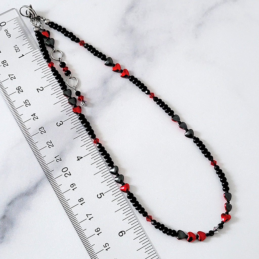 Black and red beaded necklace next to a ruler.