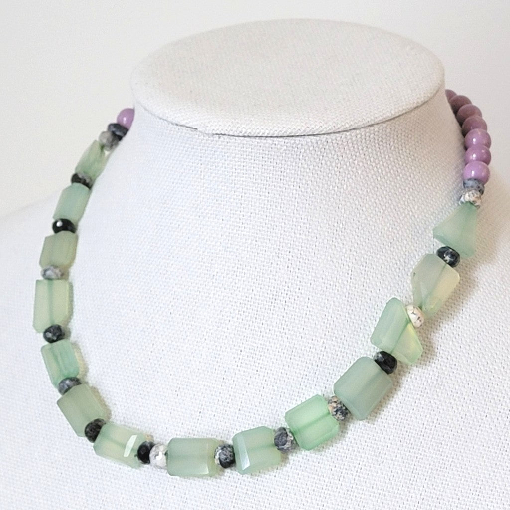 Lime green and purple gemstone beaded necklace, shown on a display stand.