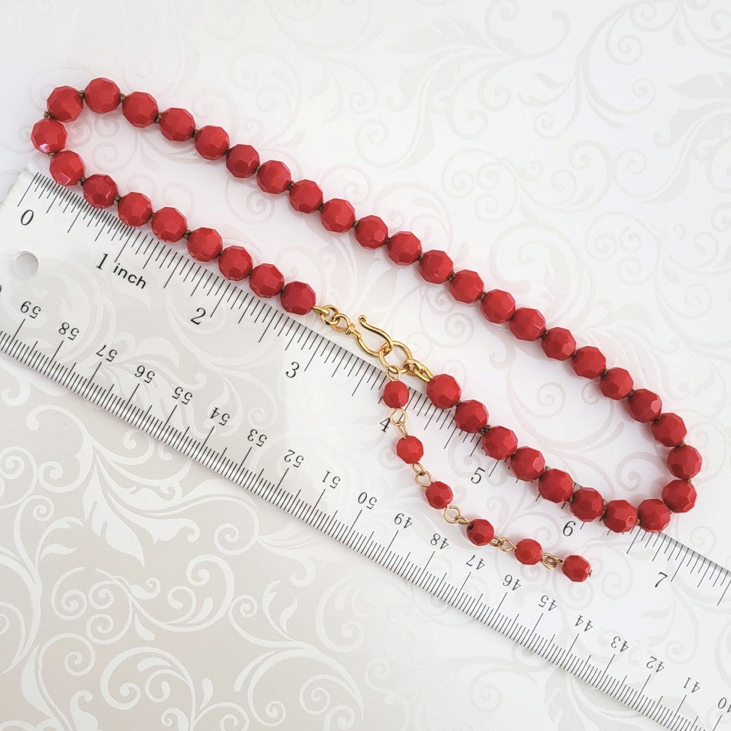 Red glass choker necklace, with beaded extender chain, shown next to a ruler.