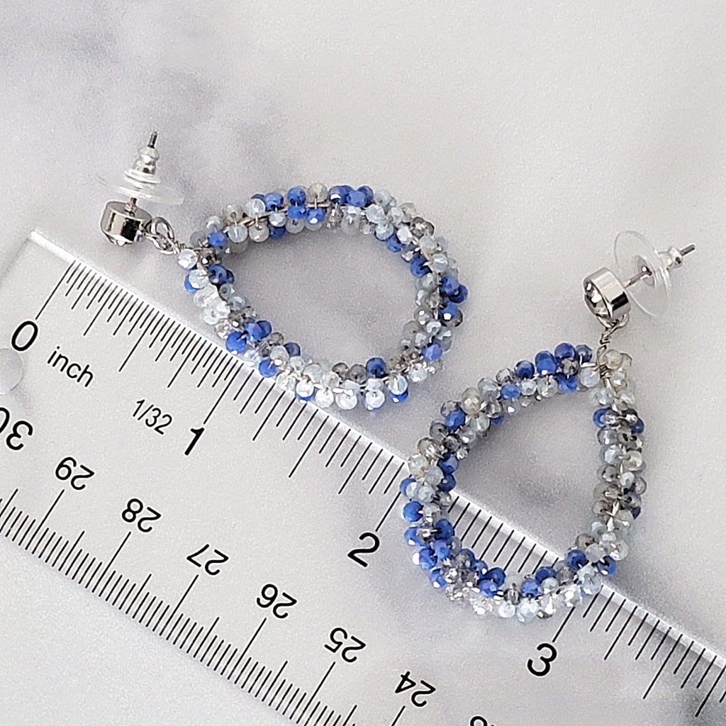 Blue beaded teardrop earrings next to a ruler.
