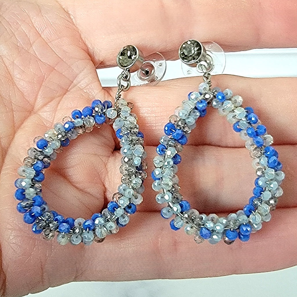 Blue dangle hoop earrings in hand.