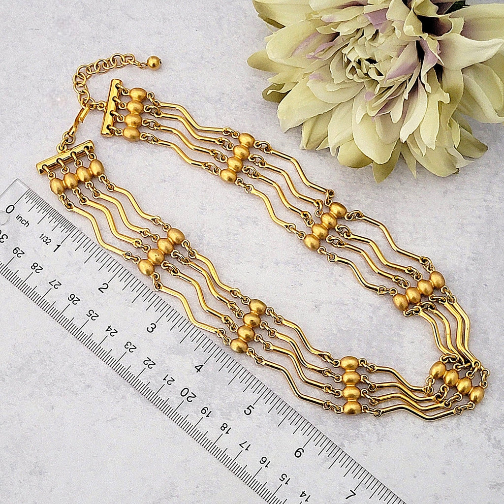 Vintage multistrand gold choker necklace with a ruler.