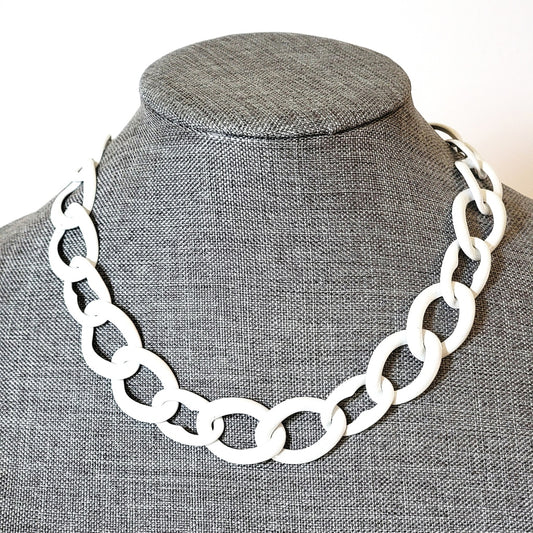 White enamel chain necklace on a gray display stand.