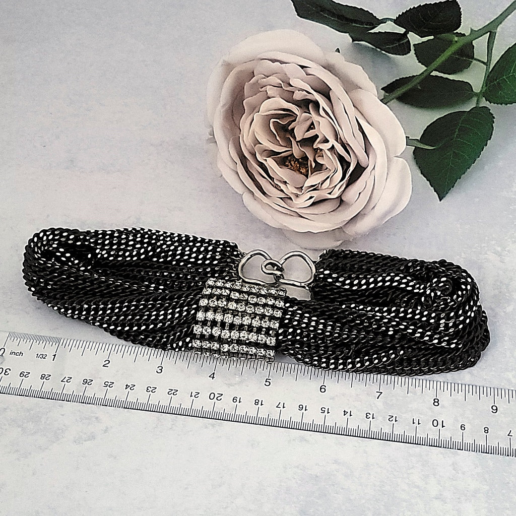 Black multi strand necklace next to a ruler.
