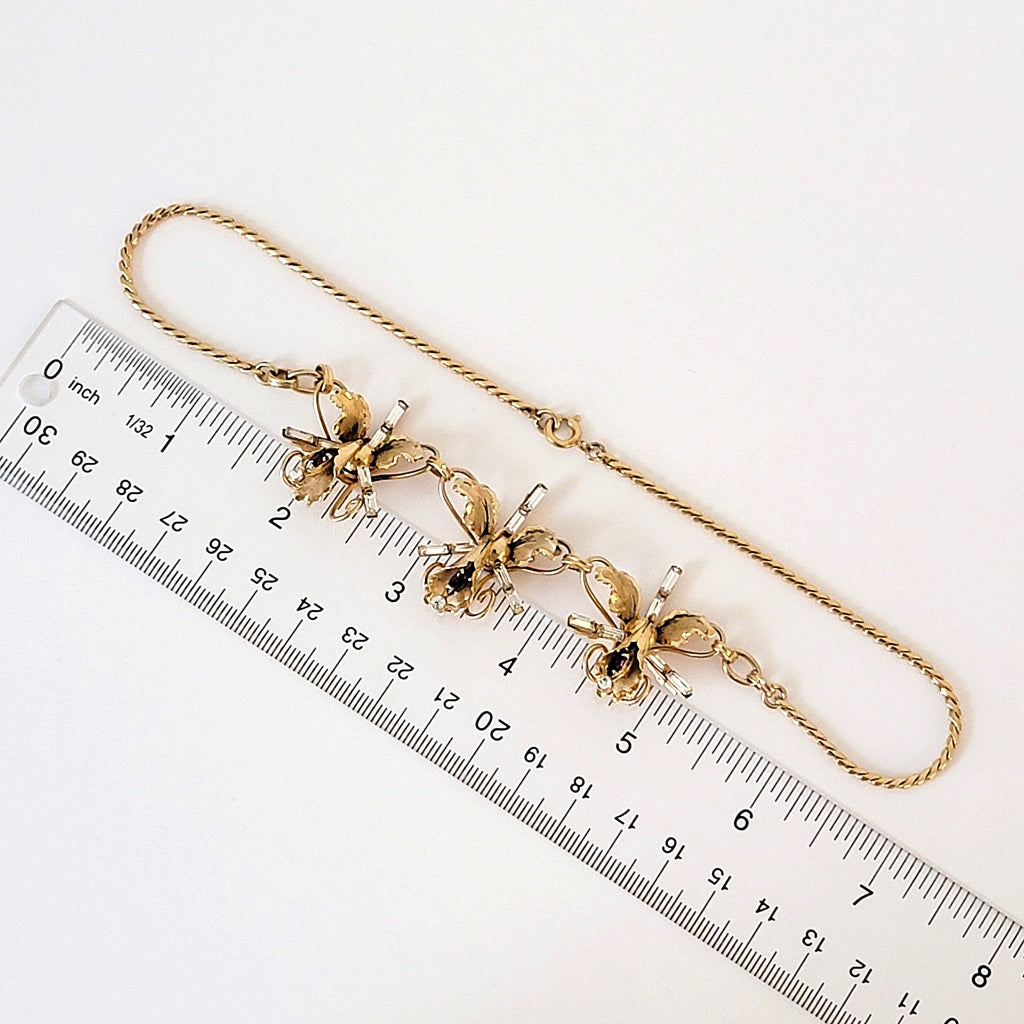 Vintage rhinestone orchid floral necklace next to a ruler.