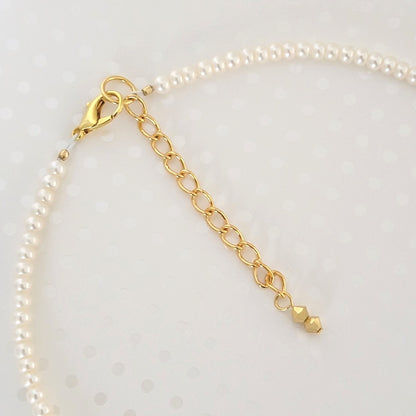 Close-up view of a gold plated clasp and extender chain, on a pearl choker.
