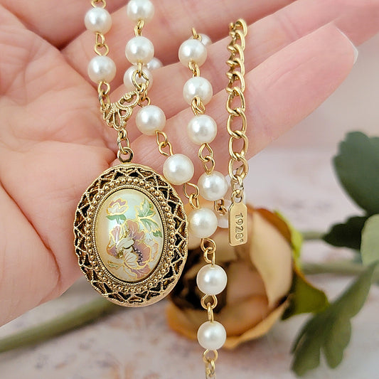 Floral locket necklace in hand.
