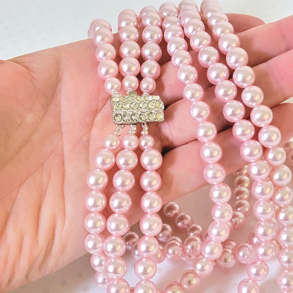 Vintage pink faux pearl necklace, with rhinestone clasp. Shown in hand, for size comparison.