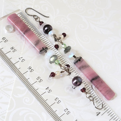 Long pink gemstone and crystal earrings, shown next to a ruler.