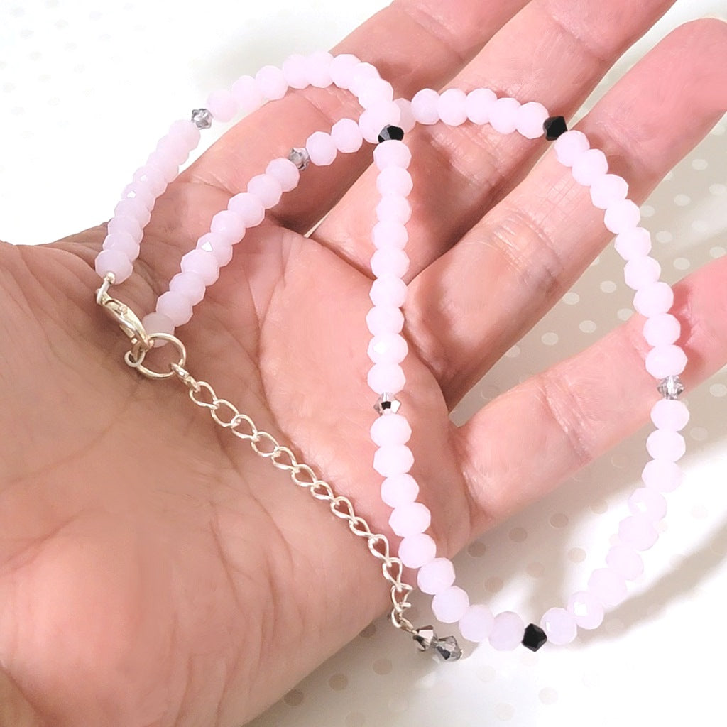 Pastel pink beaded choker necklace, shown in hand, for size comparison.