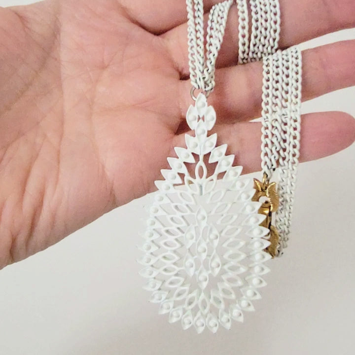 White pendant necklace in hand.