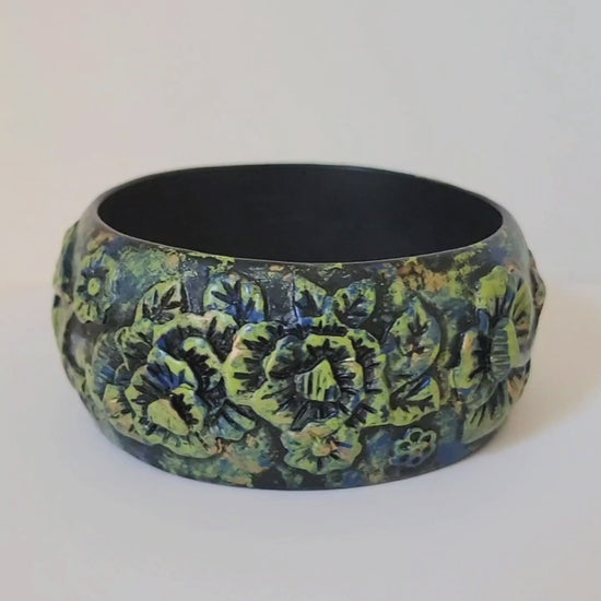 Video of a goth style wide bangle bracelet in black molded resin, with green flowers.