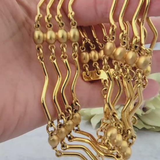 Gold tone bar link necklace in hand.