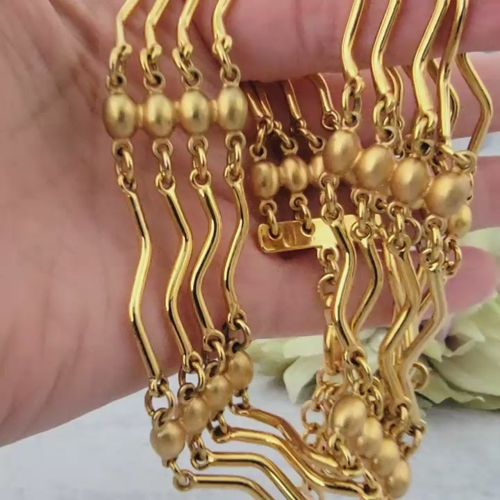 Gold tone bar link necklace in hand.