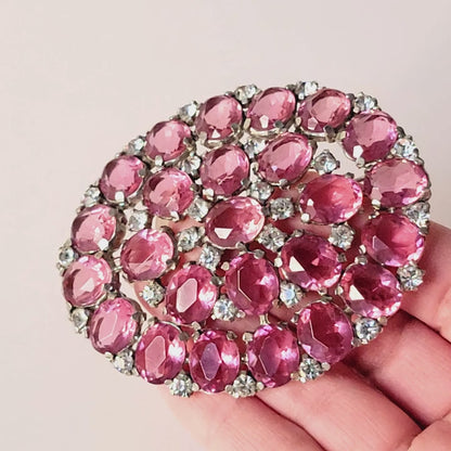 Large pink brooch in hand.