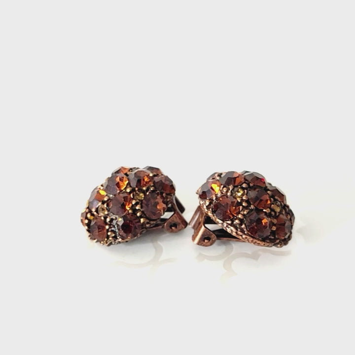 Copper tone orange rhinestone clip earrings.