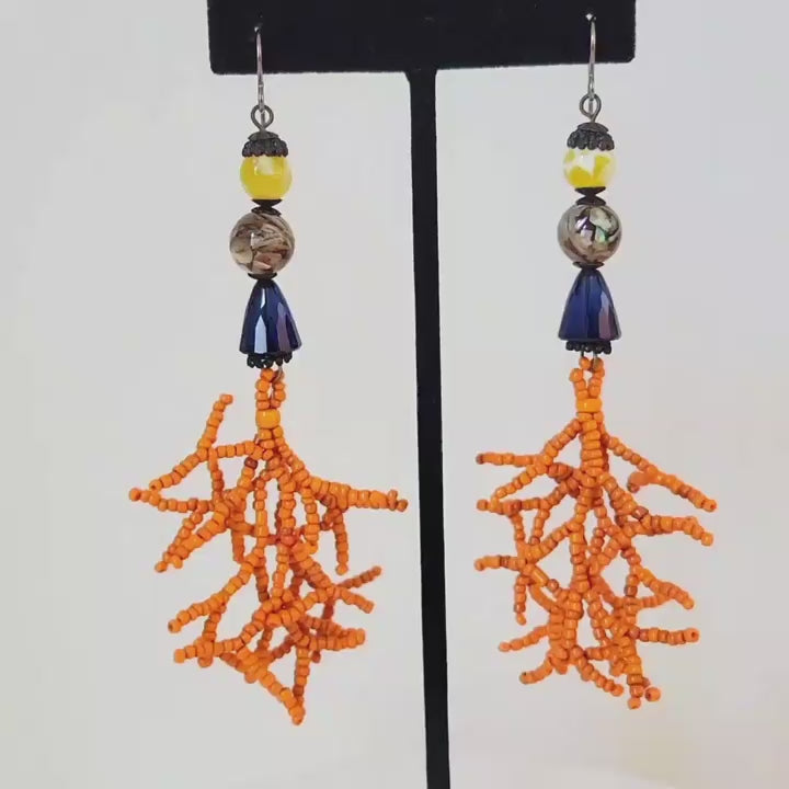 Video of long boho style dangle earrings with yellow stones, blue crystals and coral seed bead branches.