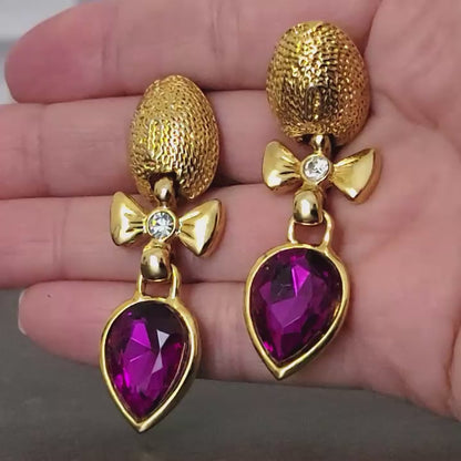 Long dangle purple rhinestone earrings in hand.