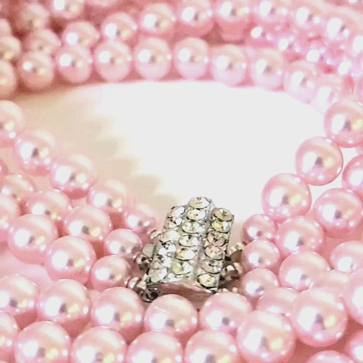Video of a pink vintage faux pearl necklace, with a rhinestone clasp.
