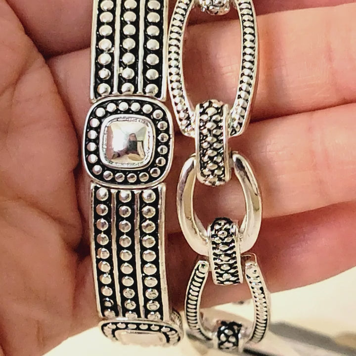 Two silver tone bracelets in hand.