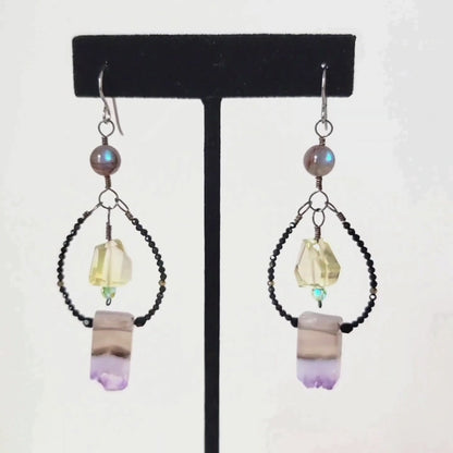 Video of a pair of dangling gemstone earrings, on a display stand.