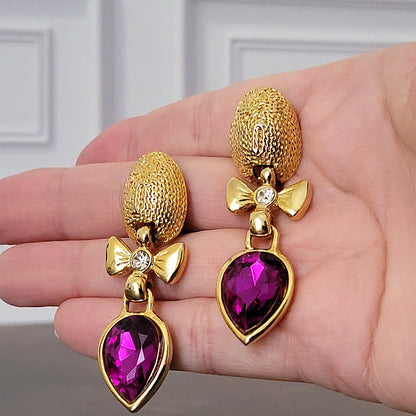 Pear shaped purple clip earrings in hand.