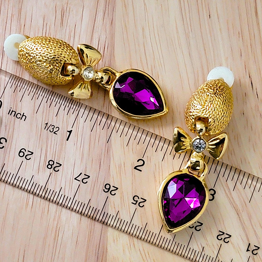 Purple clip earrings next to a ruler.