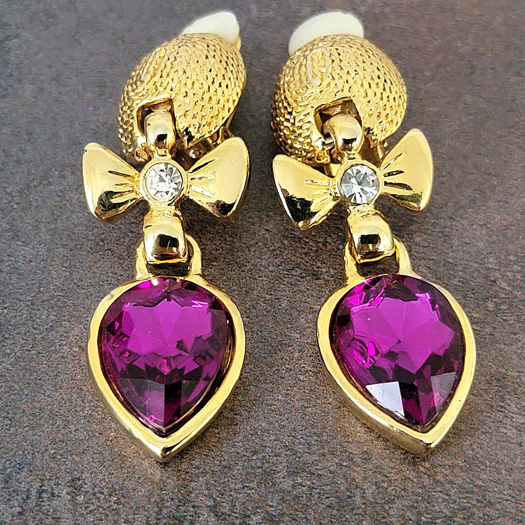 Purple glass clip earrings with gold tone bows.