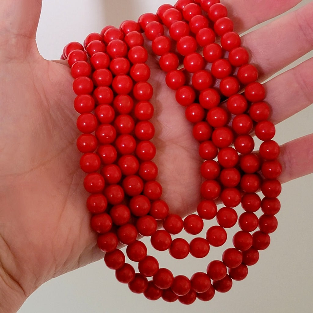 Vintage four-strand red beaded choker necklace, shown in hand, for size comparison.
