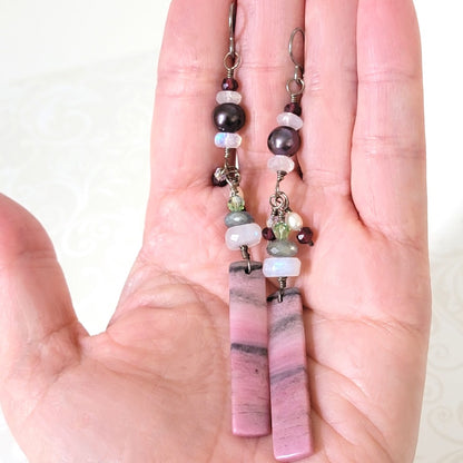 Long pink gemstone earrings, with pearls and moonstones. Shown in hand, for size comparison.