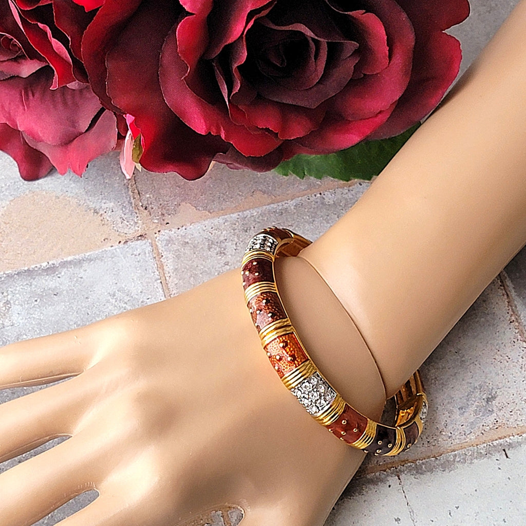 Coppery enamel bracelet on a wrist.