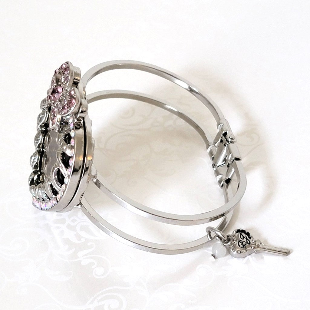 Side view of a silver tone Betsey Johnson hinged bangle bracelet.