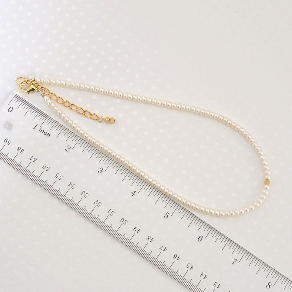 Skinny pearl choker, shown next to a ruler.