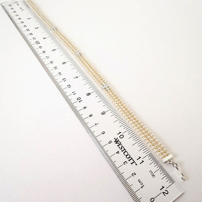 Faux pearl choker next to a ruler.