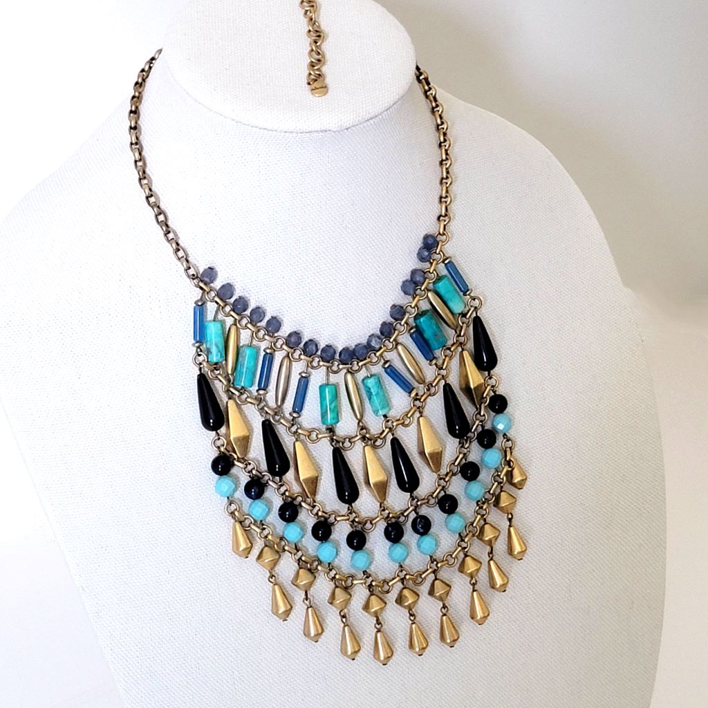 Stella and Dot blue and gold dangle bead fringe necklace, shown on a display stand.