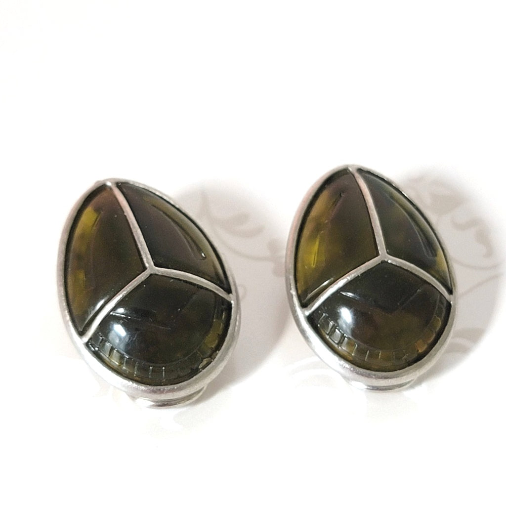 Top view of a vintage pair of Claiborne beetle earrings, in faux tortoiseshell plastic.