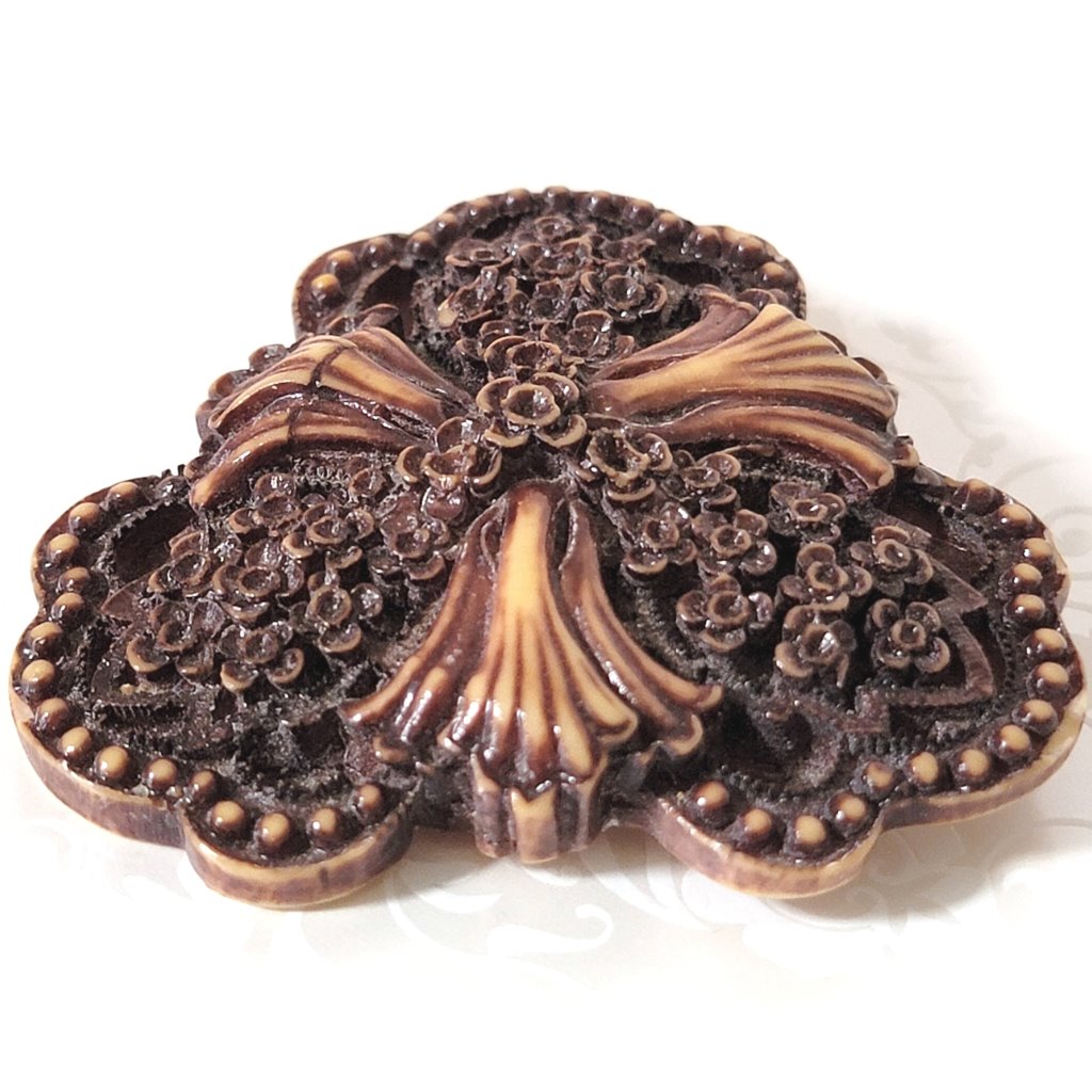 Closeup view of a vintage goth flower brooch, made of resin or plastic.
