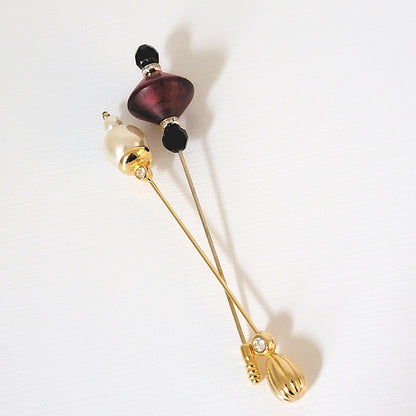 Two vintage stick pins. One faux pearls and the other black and red glass.