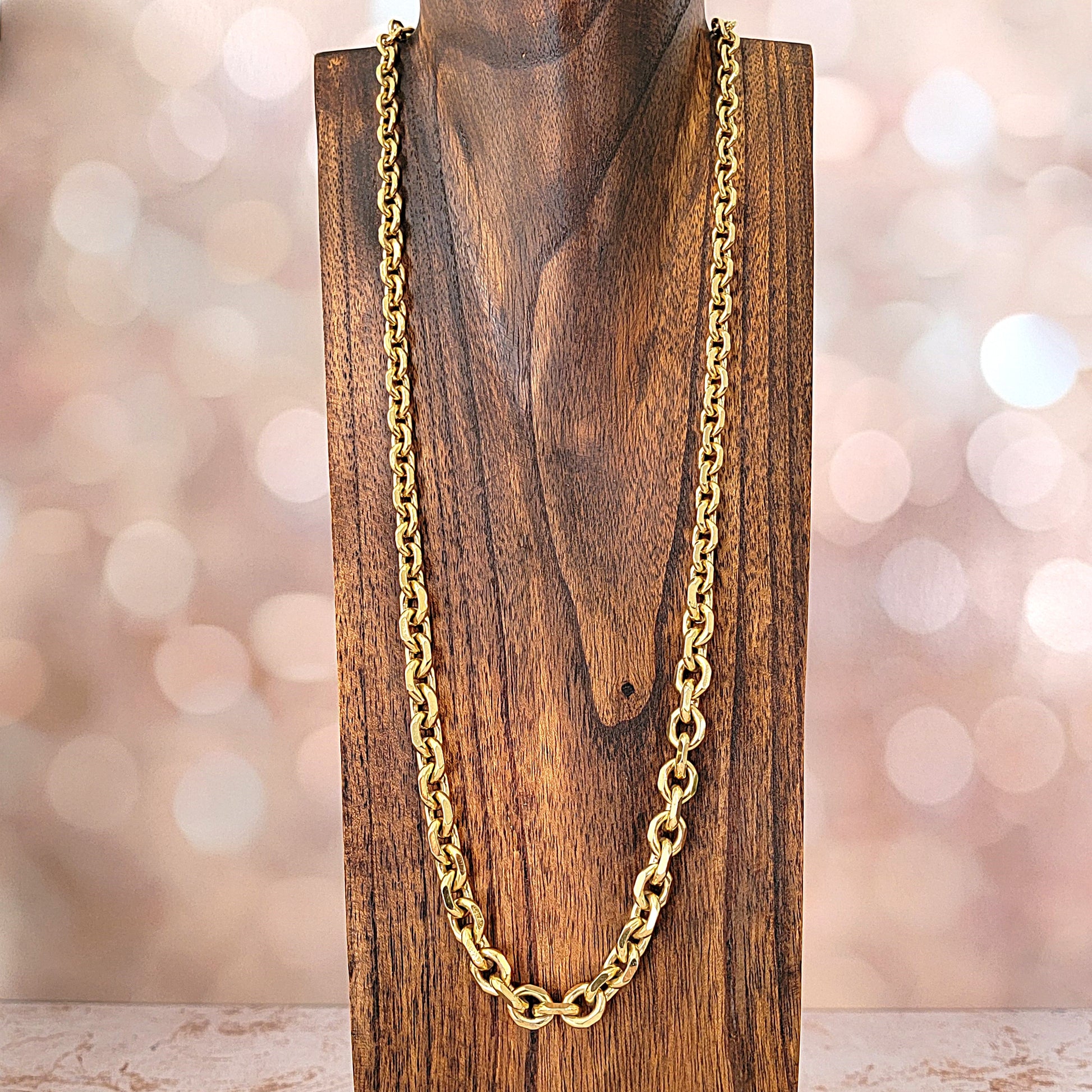 Long gold chain on a wood display stand.